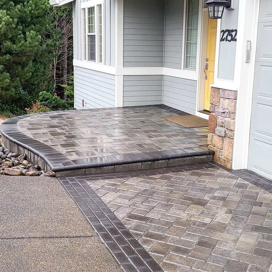 Curved paver walkway leading to a house with a yellow door