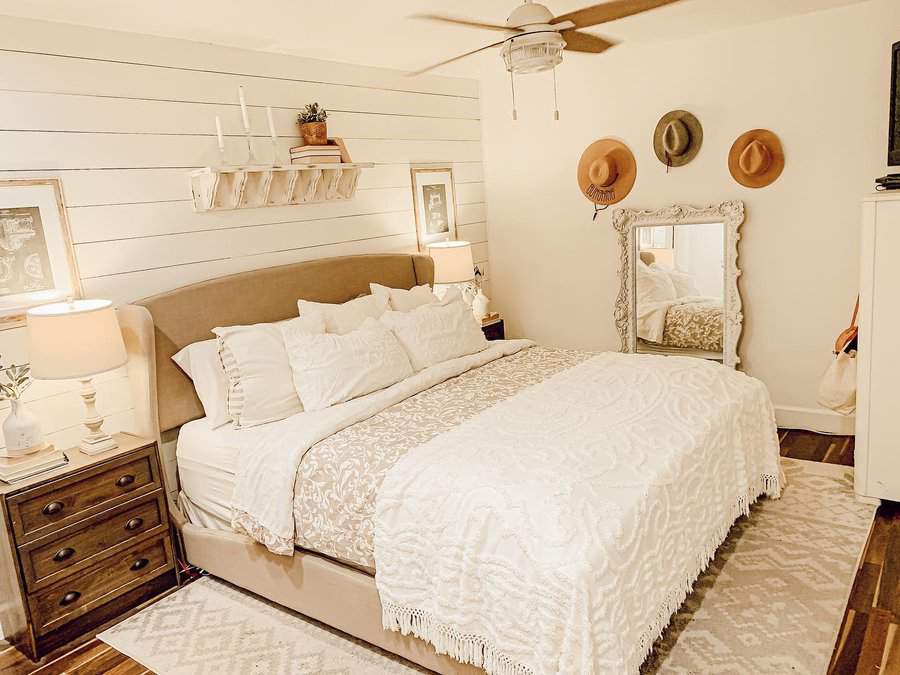 Zen bedroom with a farmhouse touch, featuring soft neutral tones, layered bedding, a shiplap accent wall, and warm rustic decor