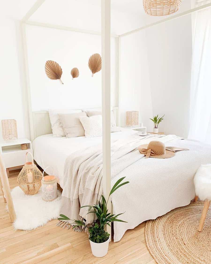 Bright bedroom with a four-poster bed, neutral decor, woven accents, and leafy plants on a wooden floor