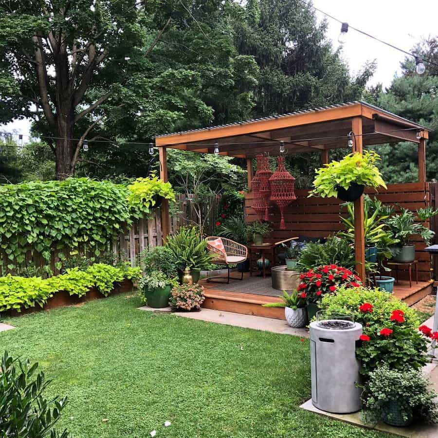 Cozy garden with a wooden pergola, string lights, lush greenery, potted plants, and colorful flowers on a well-manicured lawn