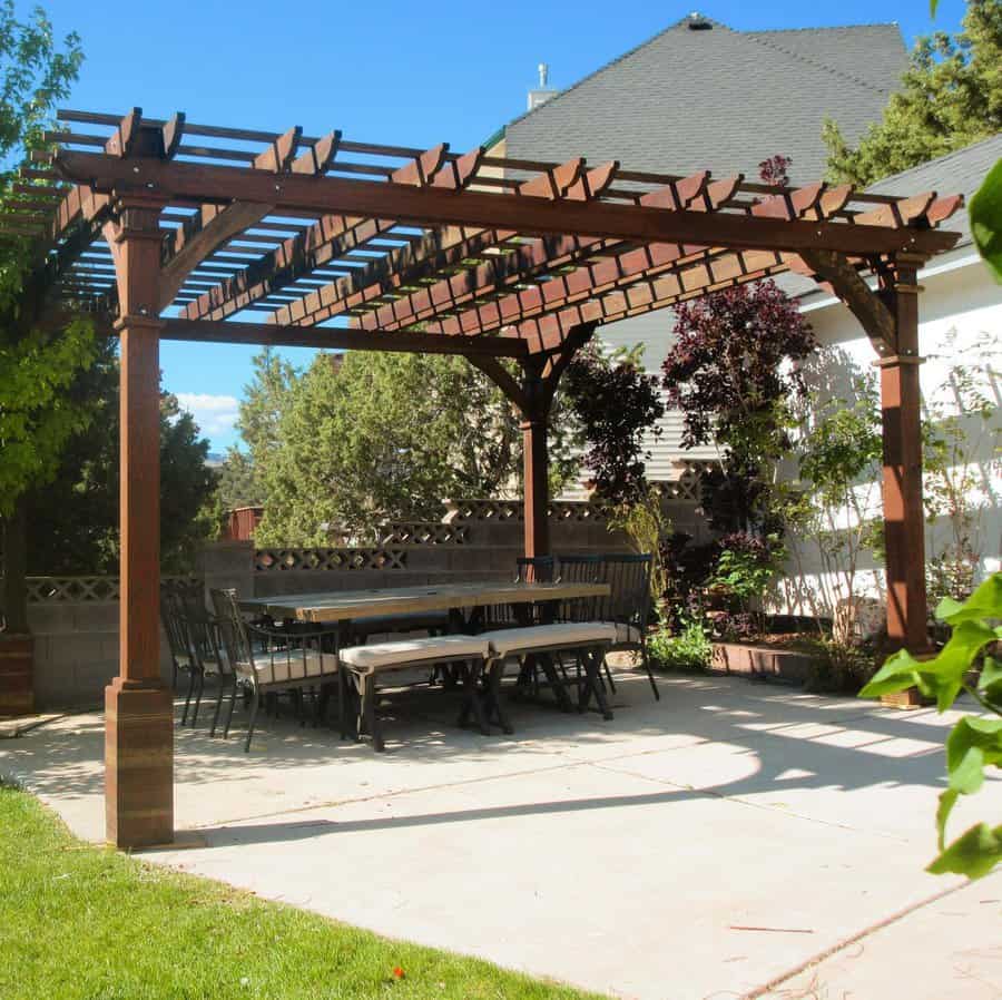 Wooden pergola over patio dining area with greenery