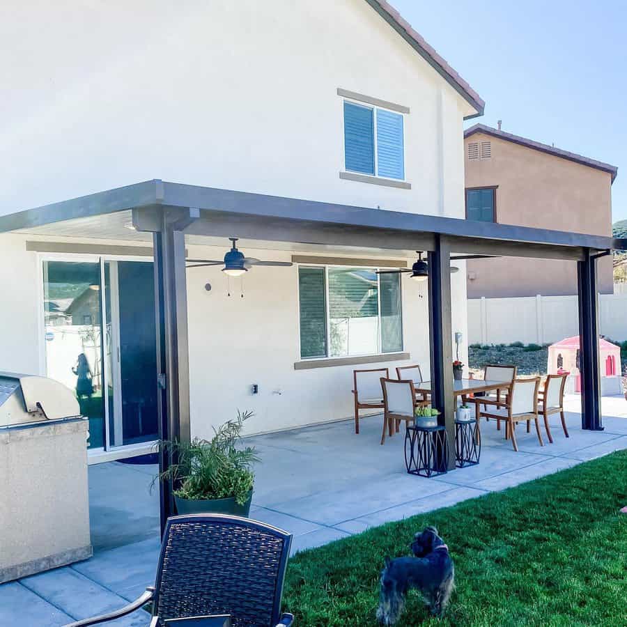 Modern covered patio with dining area and a dog on grass