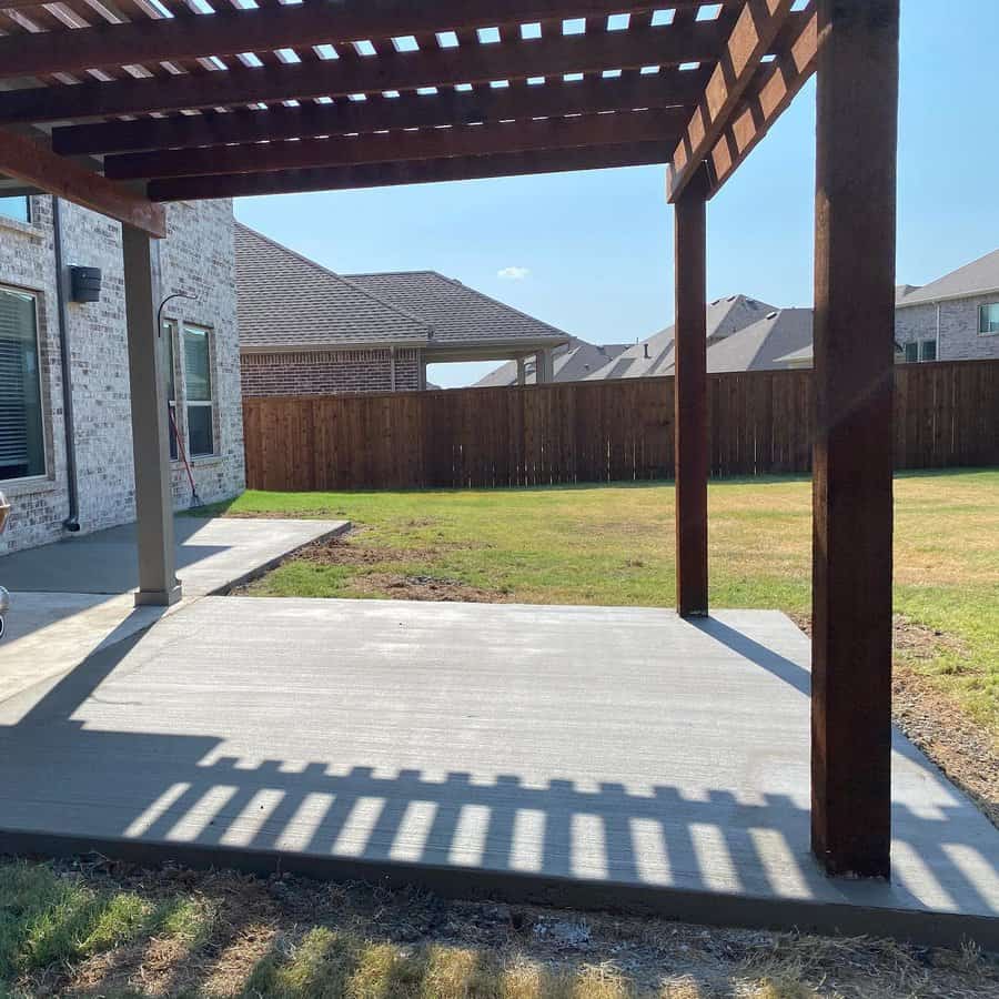 Concrete patio with wooden pergola casting shadows