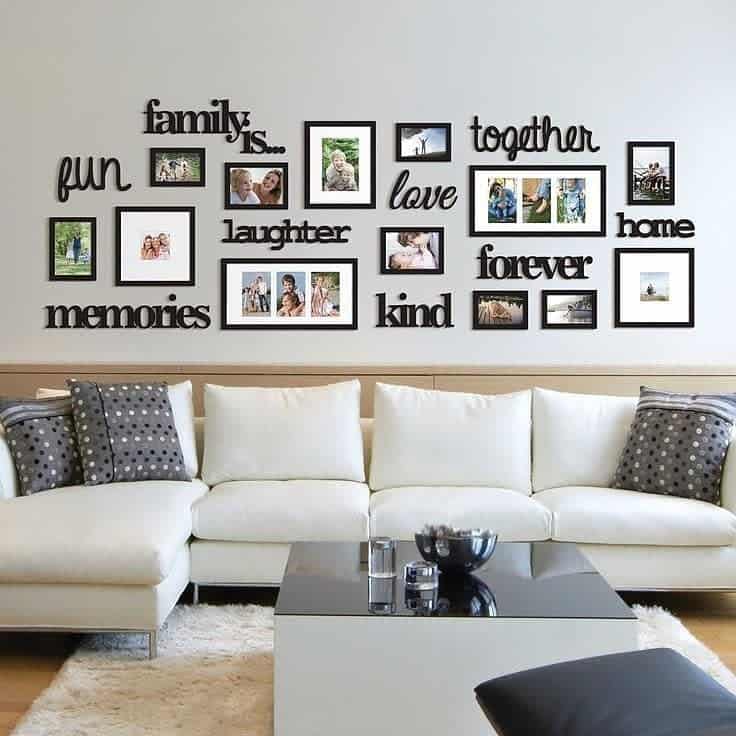 A living room wall with a collage of framed family photos and words like "family," "fun," "love," and "home" above a white sofa