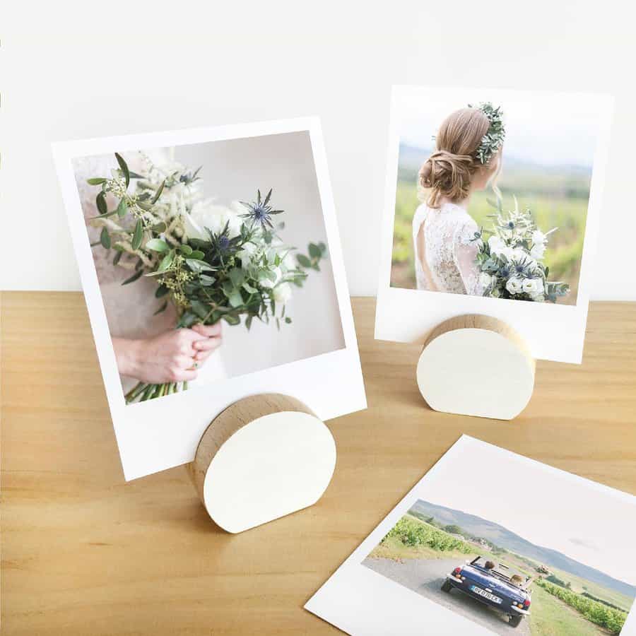 Two photo prints in wooden holders: one of a bouquet, another of a woman with flowers in her hair; a wedding photo lies flat below