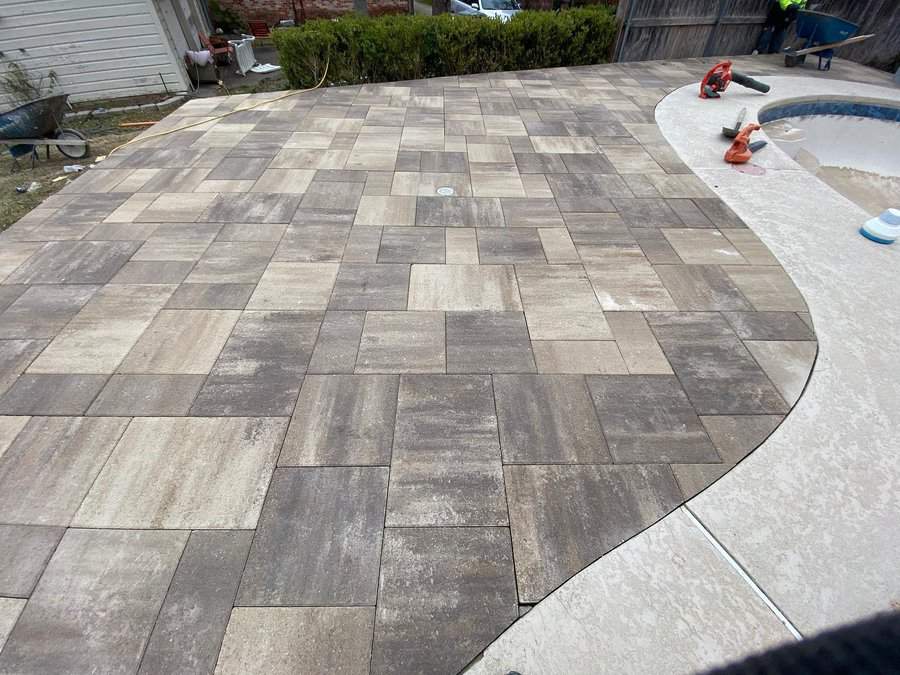 Patterned paver patio curving near a pool edge