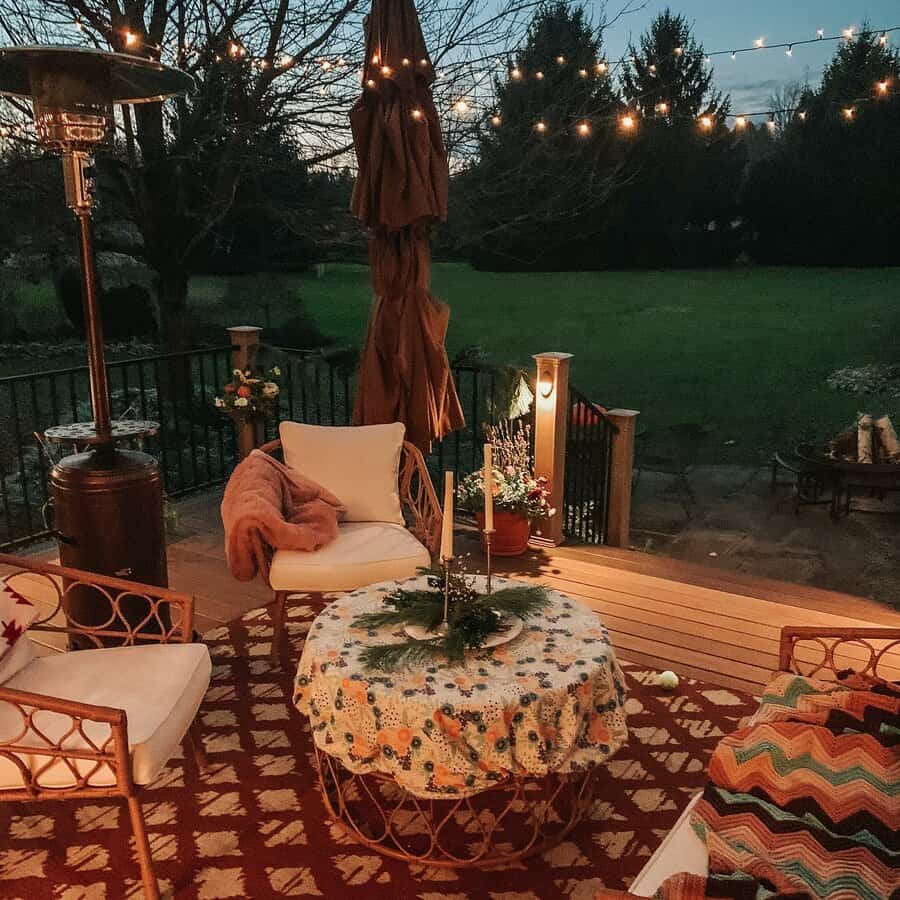 Cozy patio with wicker chairs, a table with candles, and string lights, overlooking a lawn at dusk