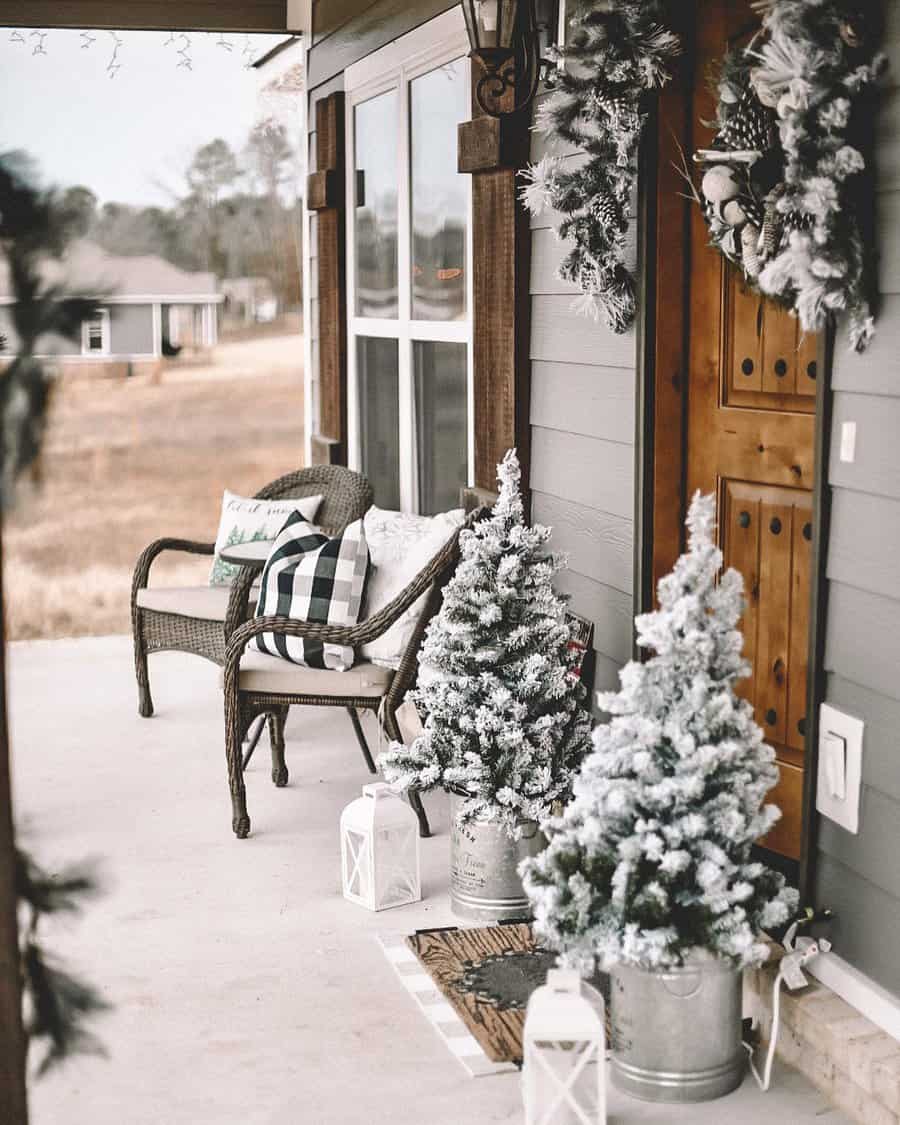 Cozy winter porch with frosted mini trees, lanterns, and a wicker chair with pillows