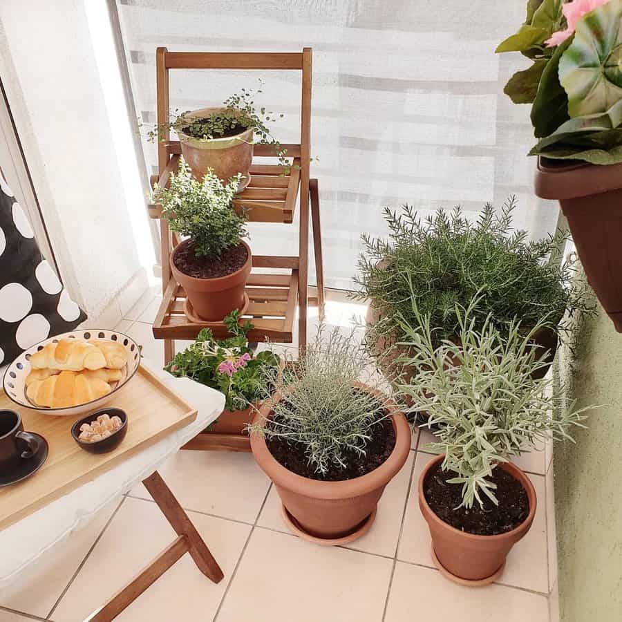 Cozy balcony with a wooden plant stand, potted herbs, a table with coffee and snacks, and a polka-dotted chair cushion