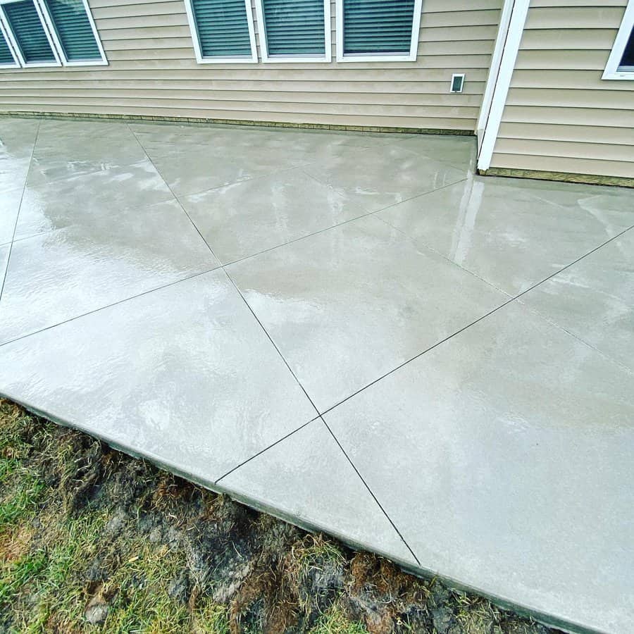 Sleek poured concrete patio beside a house with windows