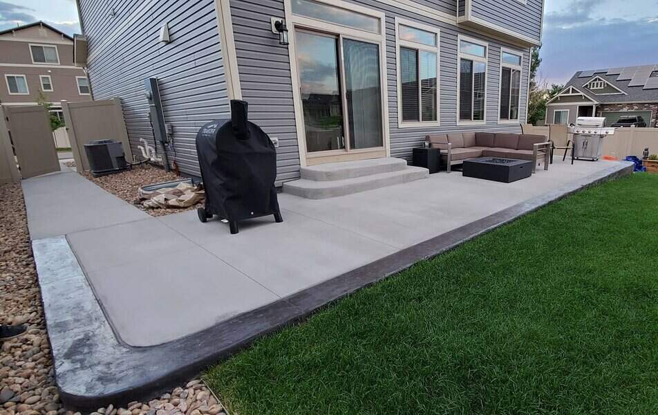 Extended concrete patio with furniture and BBQ grill