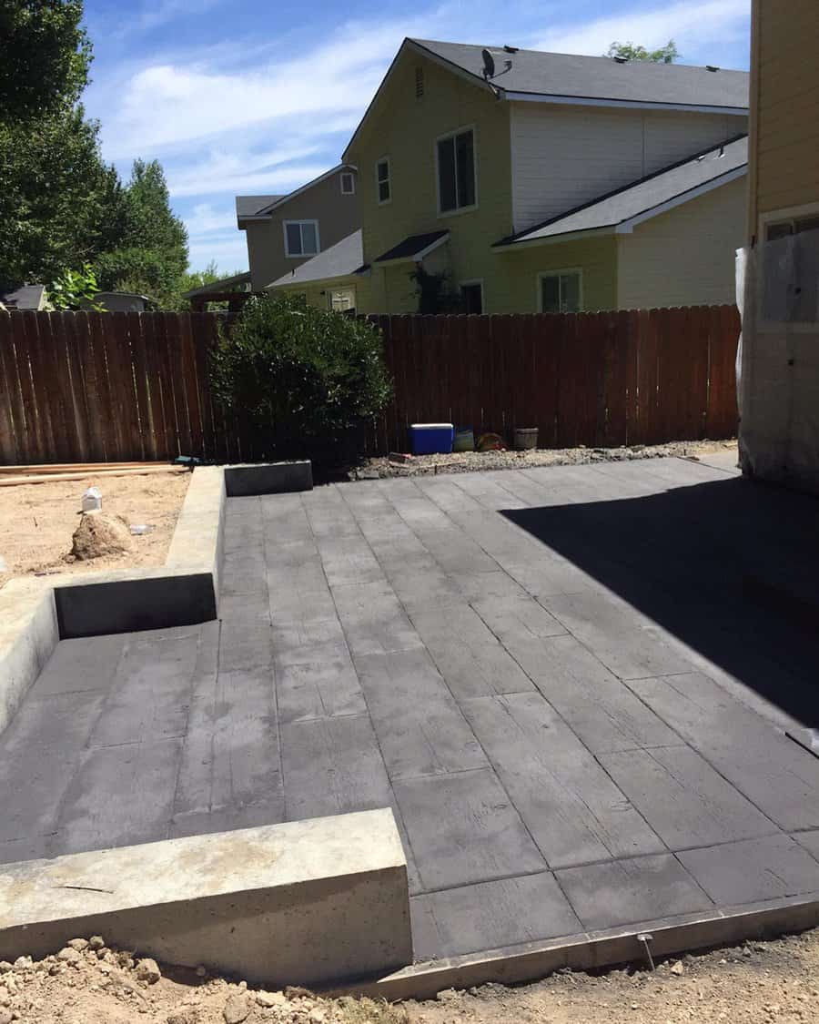 Newly poured dark concrete patio in a backyard