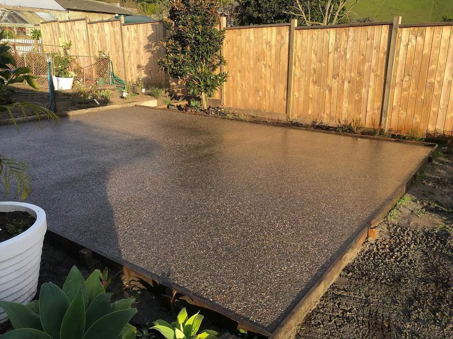 Exposed aggregate concrete patio in a fenced backyard