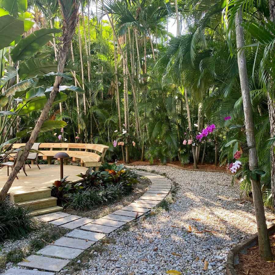 Secluded Florida garden with towering palm trees, blooming orchids, a gravel pathway, and a cozy wooden seating area for a peaceful tropical retreat