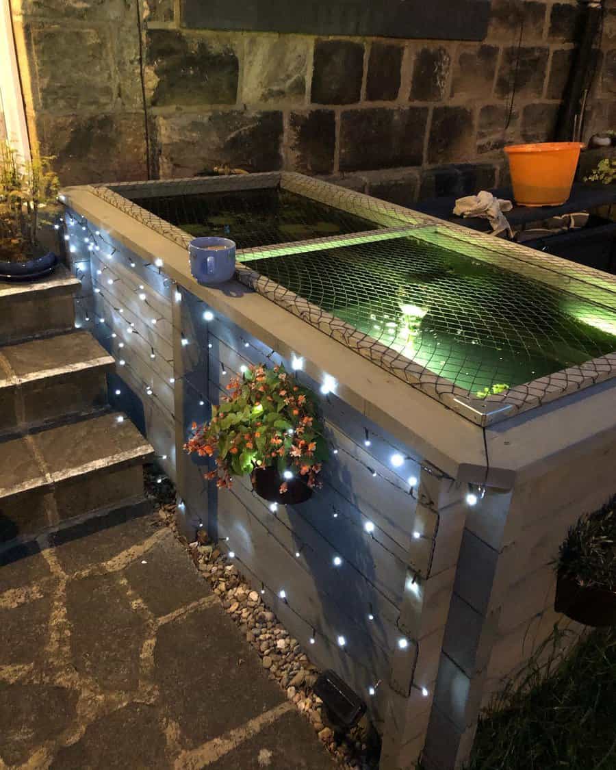 Illuminated raised pond with fairy lights and plants