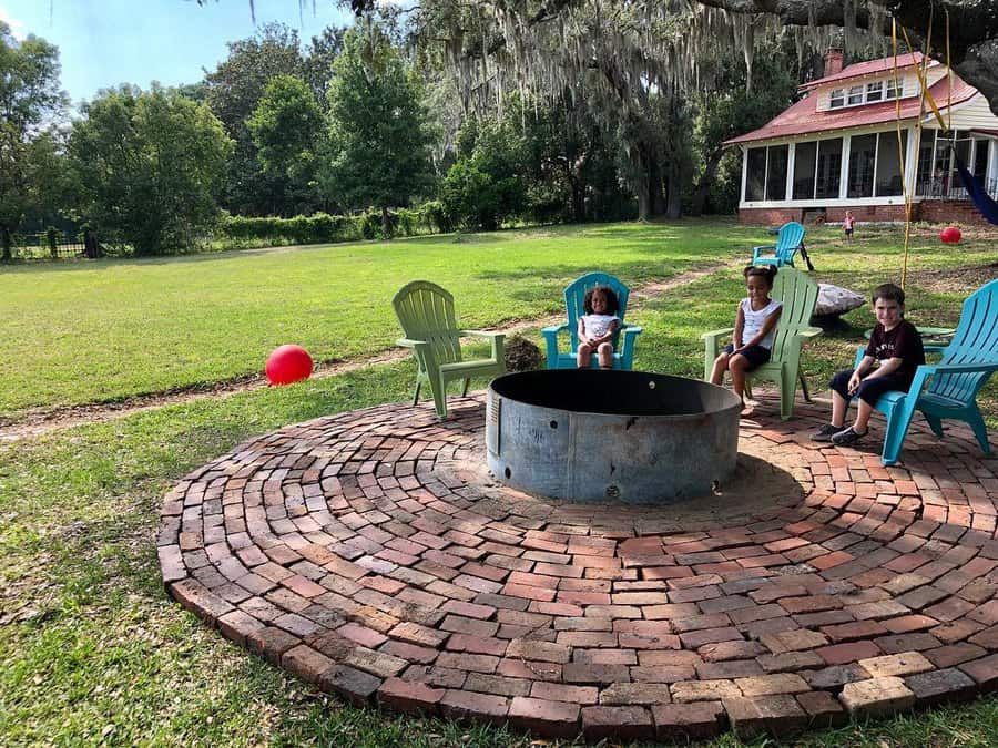 Children seated around a fire pit on a circular brick patio