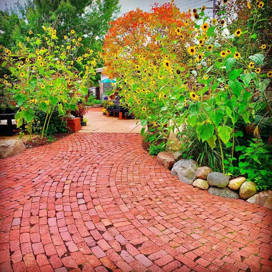 Curved red brick path through a vibrant garden with sunflowers