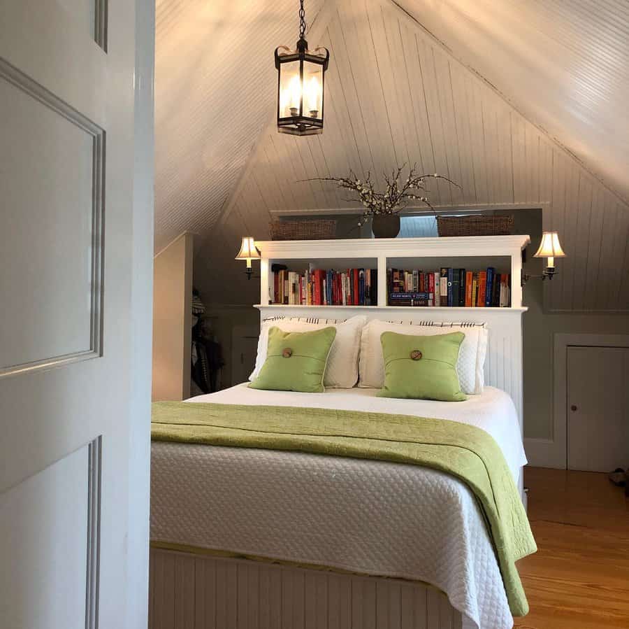 Cozy attic bedroom with a built-in bookshelf headboard, soft lighting, and green accents for a fresh and inviting retreat.