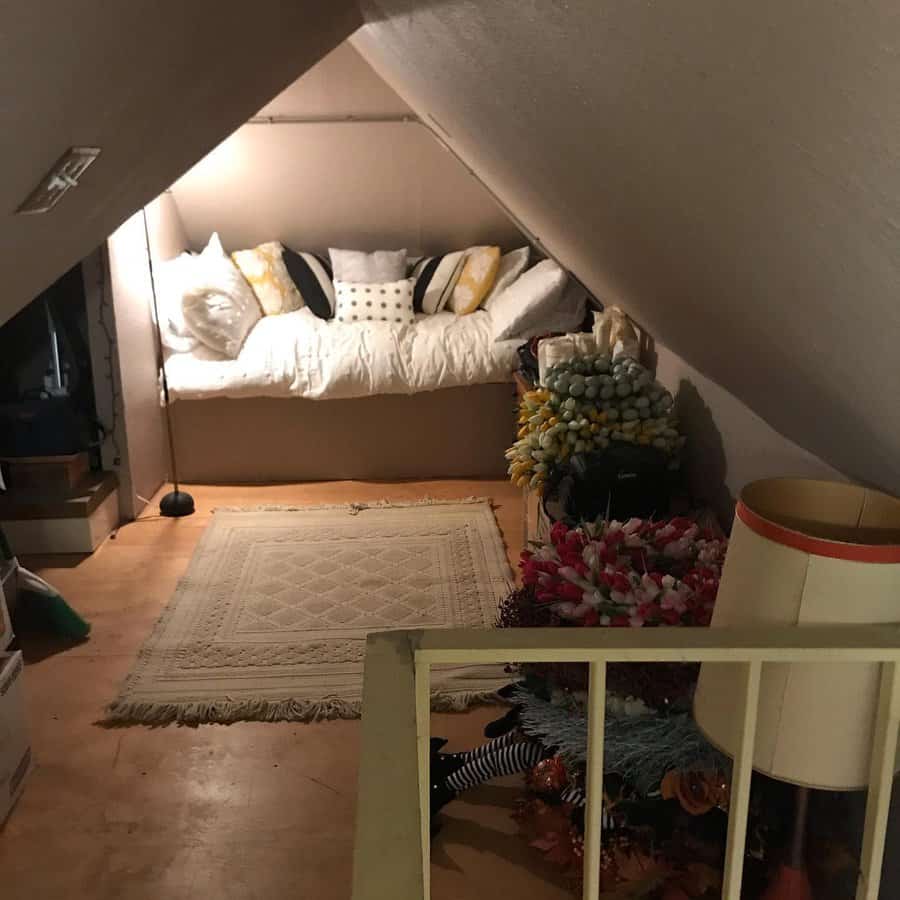 Cozy attic nook with a built-in daybed, layered pillows, and warm lighting, creating a snug retreat perfect for relaxation and storage.