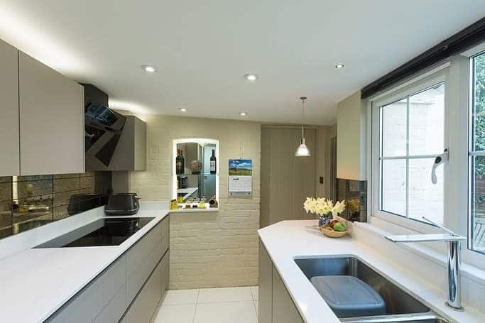 Modern kitchen with white countertops, gray cabinets, and window above the sink