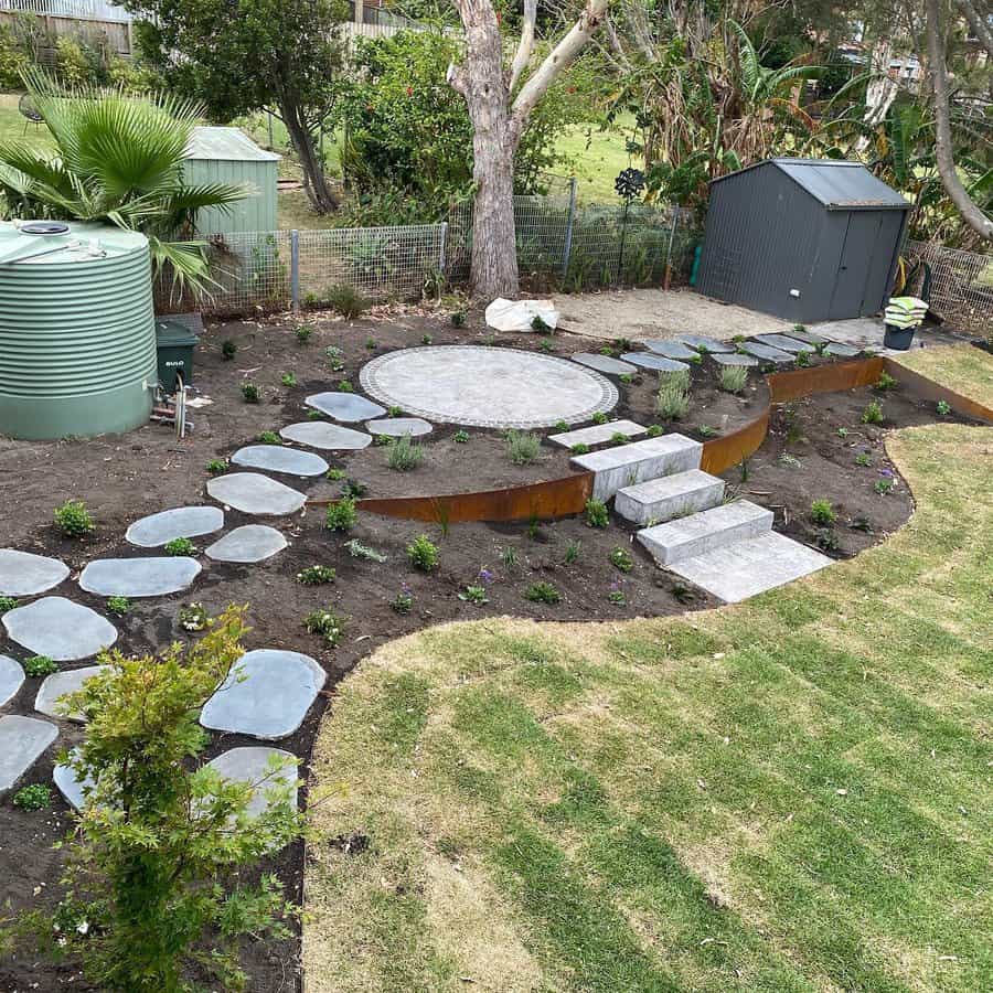 Tiered garden layout with stepping stones leading to a circular patio. Minimalist design features rusted steel edging, native plants, and a mix of gravel and turf for a low-maintenance, modern backyard look.