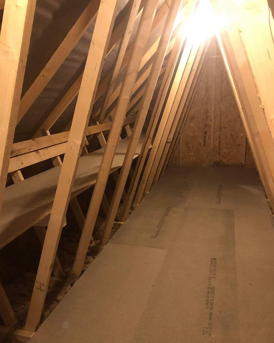 Partially finished attic storage space with wooden framing, a newly boarded floor, and built-in side shelves for organization.