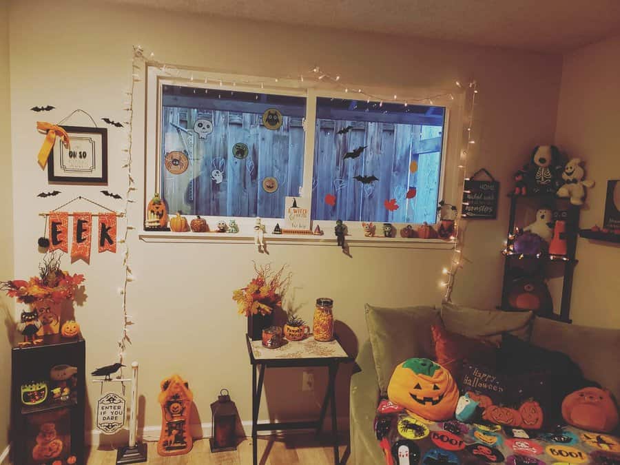 Room decorated for Halloween with pumpkins, bats, and festive lights around a window