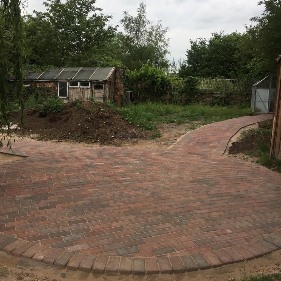 Brick patio with curving path and rustic backdrop