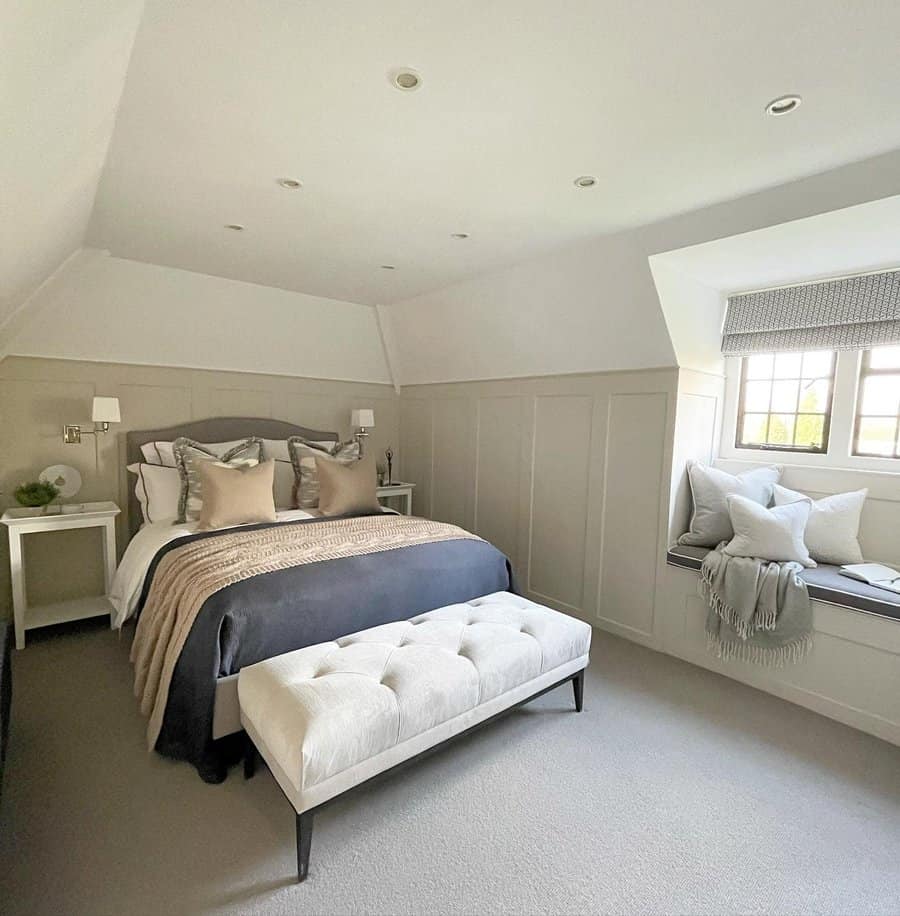 Elegant attic bedroom with neutral tones, a tufted bench, and a cozy window seat, creating a sophisticated and serene retreat.