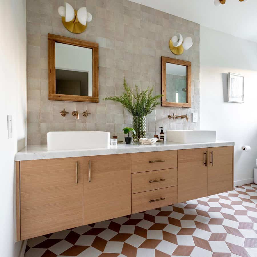 Modern bathroom with floating wood vanity, dual sinks, two mirrors, and geometric tile floor featuring green plant decorates countertop