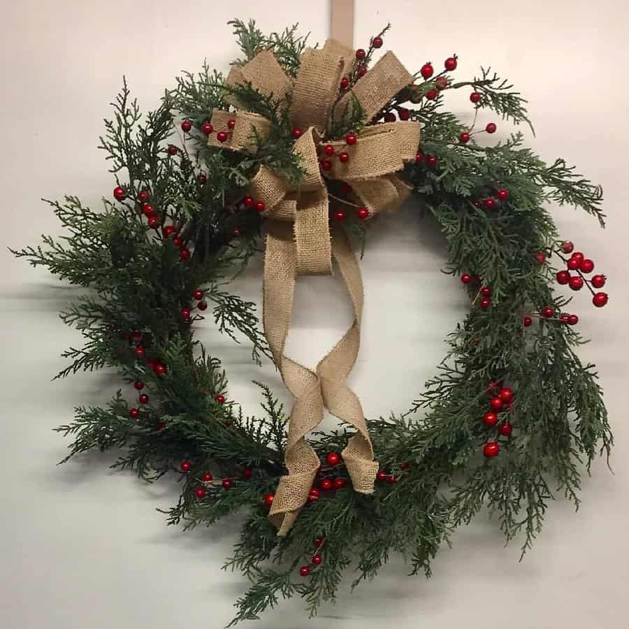 Festive wreath with green foliage, red berries, and a large burlap bow