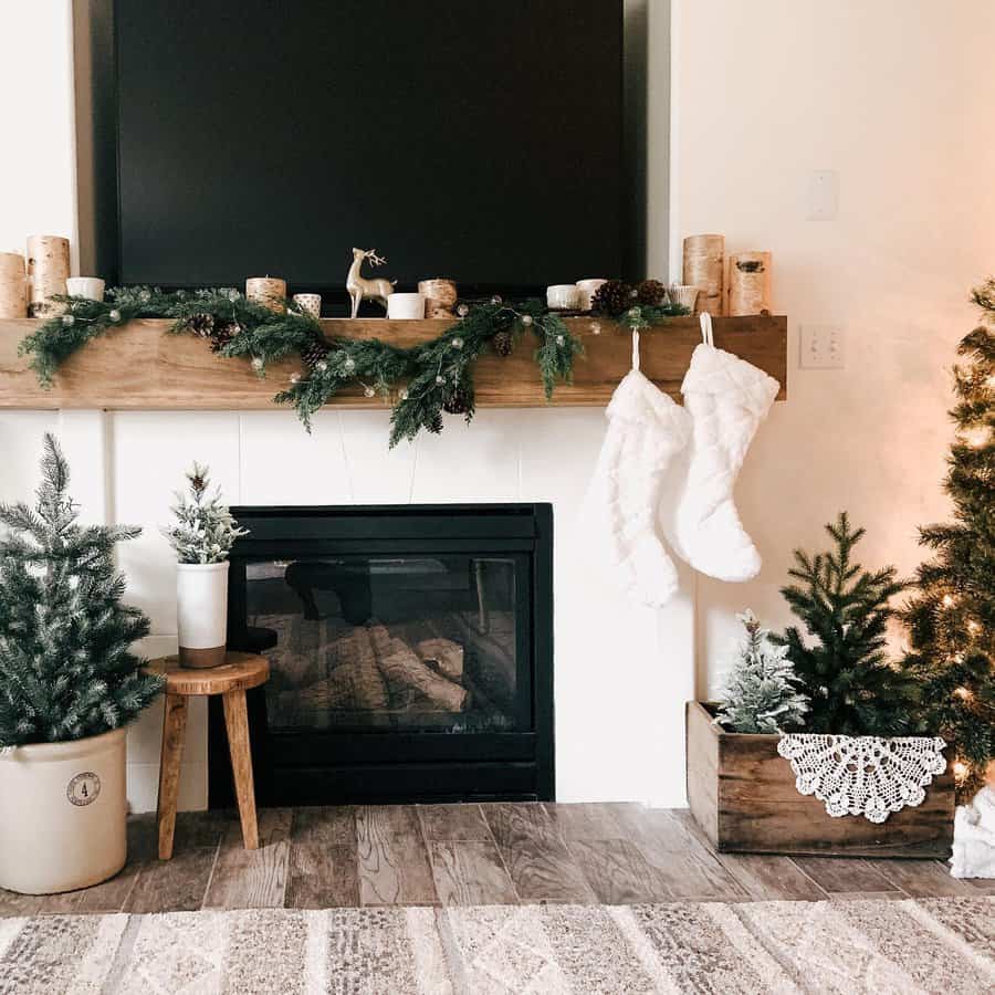 Cozy Christmas fireplace with stockings, garland, and small decorated trees