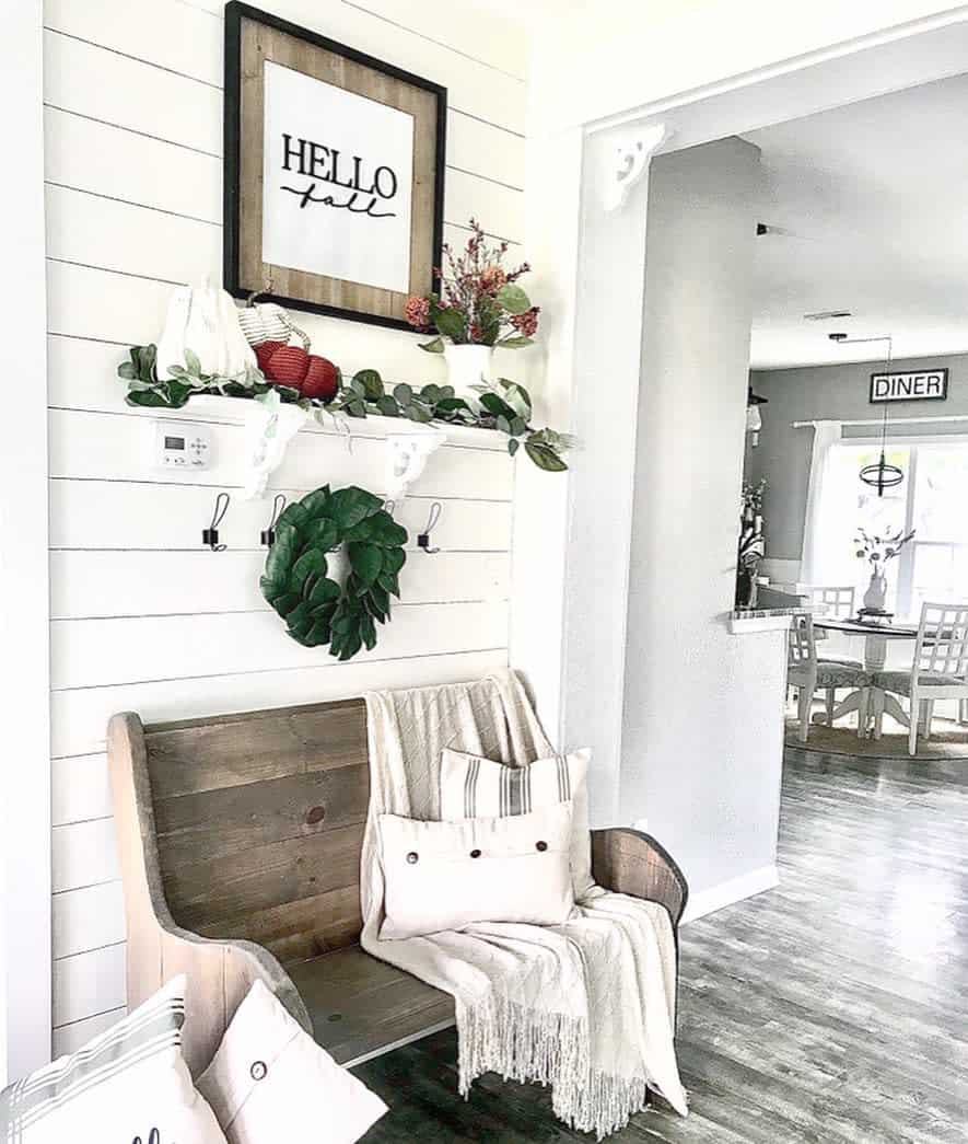 Rustic farmhouse entryway with a wooden bench, shiplap walls, cozy fall decor, and a welcoming "Hello Fall" sign for a warm seasonal touch