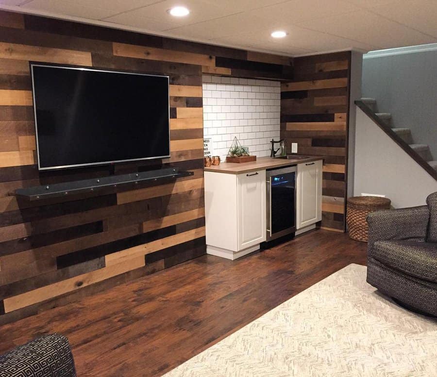 Rustic basement with a reclaimed wood accent wall, built-in kitchenette, subway tile backsplash, and cozy seating for a warm and inviting space.