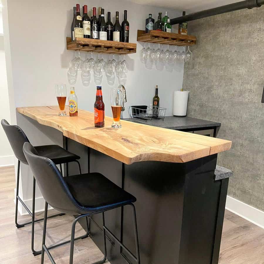 Rustic basement bar with a live-edge wood countertop, black cabinetry, open wine racks, and cozy seating for a stylish and inviting gathering space.