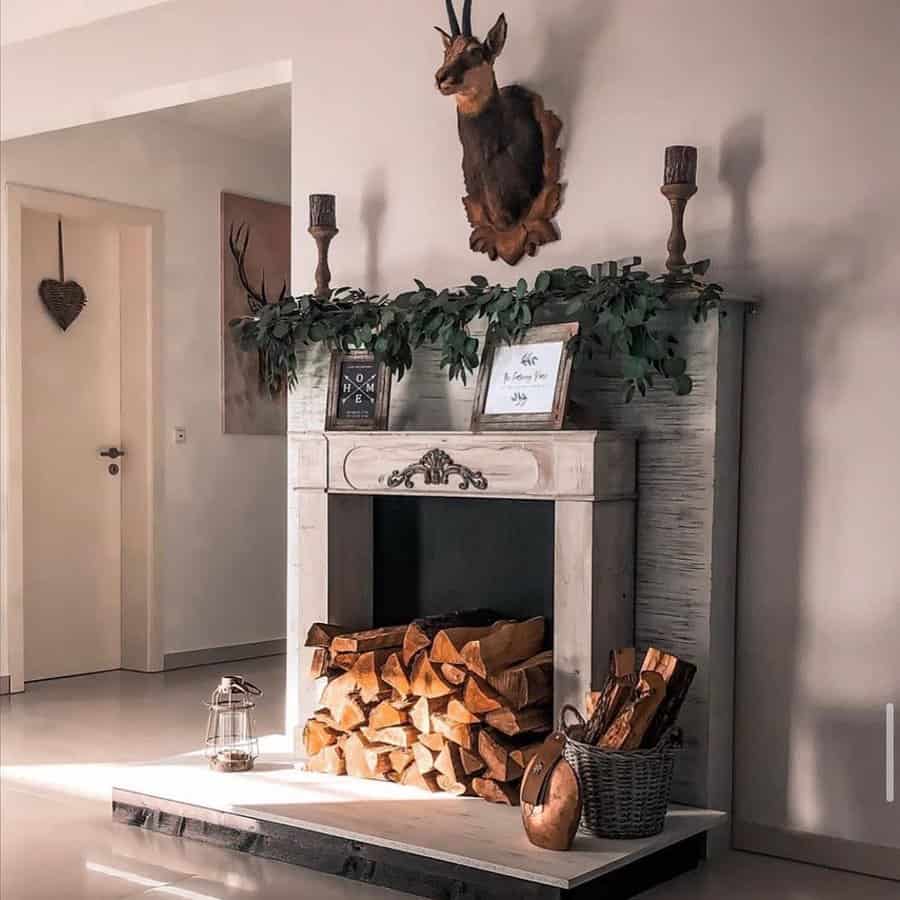 Cozy living room with a decorated fireplace, stacked firewood, a mounted deer head, and a wicker basket with a lantern nearby