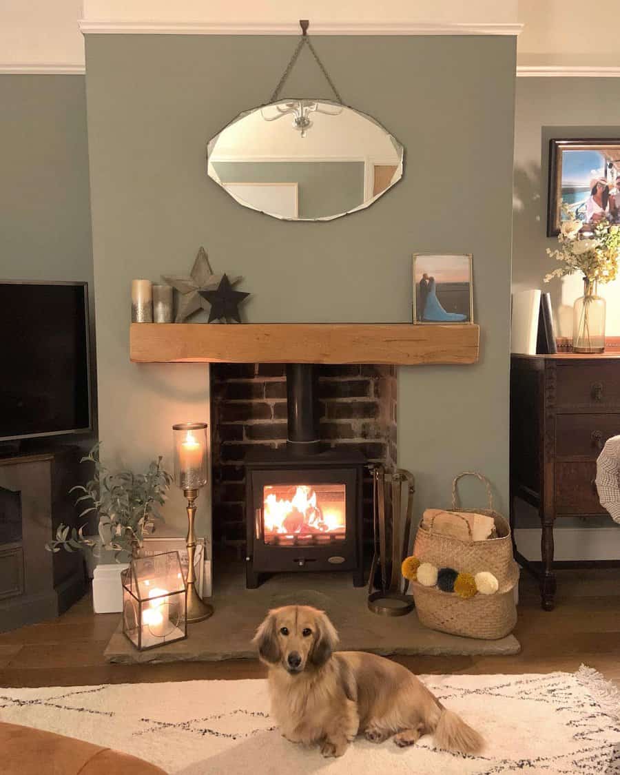 Cozy living room with a lit fireplace, mirror above mantle, candles, and a fluffy dog laying on the rug