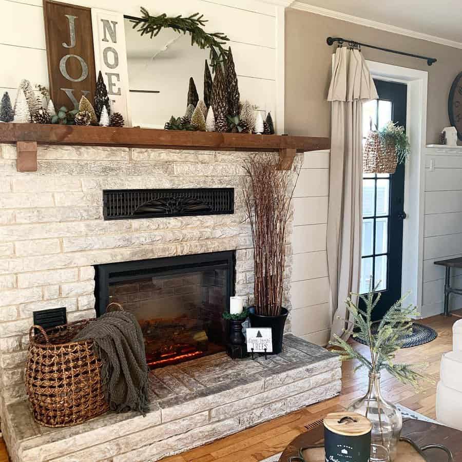 Cozy living room with a stone fireplace, holiday decor, and a basket with a blanket. A door with a window is on the right