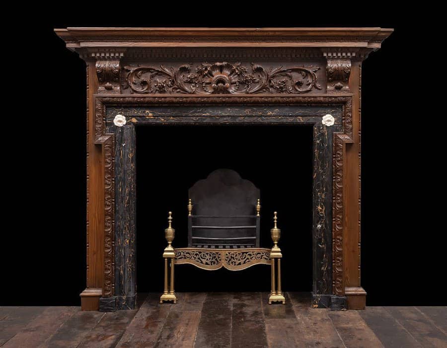 A vintage ornate fireplace mantel made of dark wood and marble, featuring intricate carvings and brass accents, adding a luxurious, classic touch