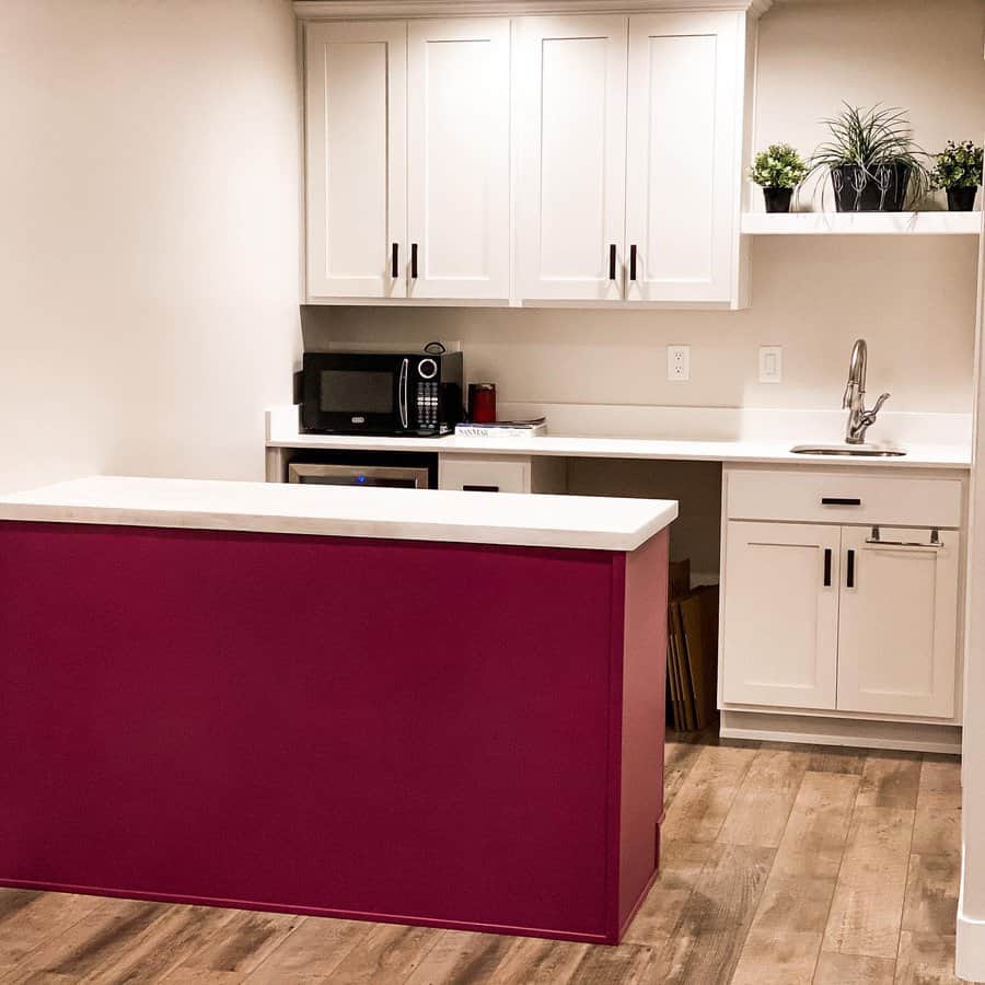 Warm wood-look flooring adds rustic charm to this modern kitchen, complementing white cabinetry and a bold magenta island for a stylish contrast