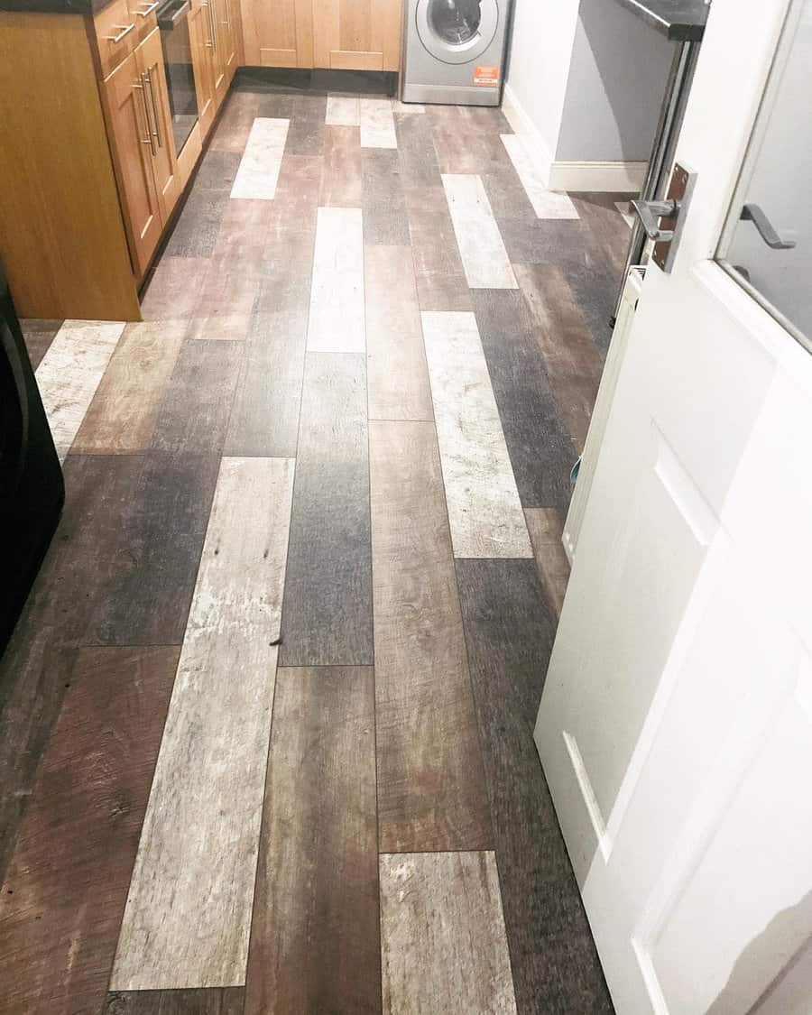 Rustic multi-toned wood flooring adds depth and character to this cozy kitchen, complementing warm wooden cabinetry for a timeless, inviting look