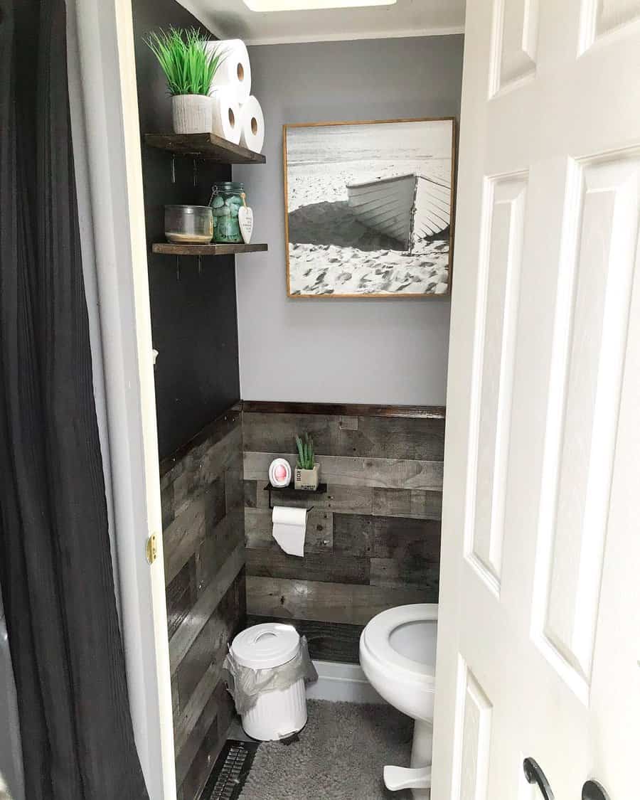 A rustic RV bathroom with wooden accents, minimalist shelving, a framed beach photo, and plants, offering a clean, functional, and cozy vibe.