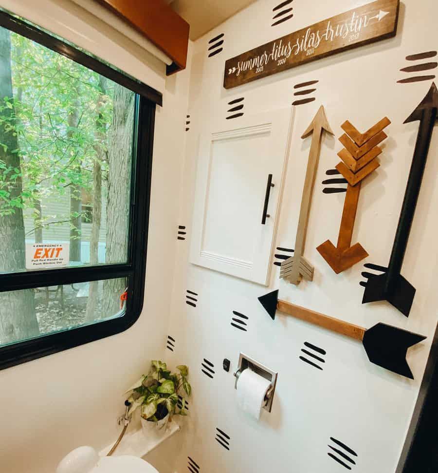 A rustic RV bathroom with a creative arrow-themed decor on the walls, a plant, and a wooden sign, creating a personalized and stylish atmosphere.