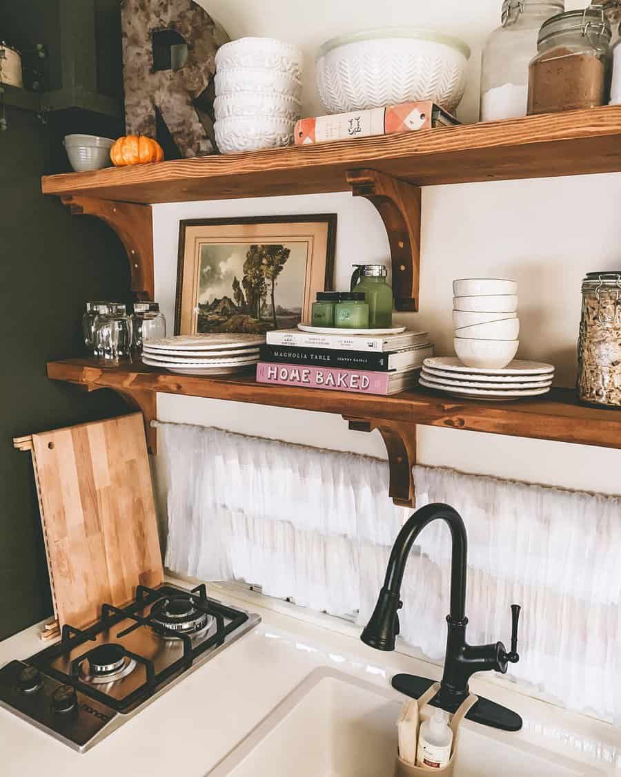 A rustic RV kitchen with wooden shelves filled with cozy decor, kitchen essentials, books, and a small pumpkin, creating a homely and functional space.