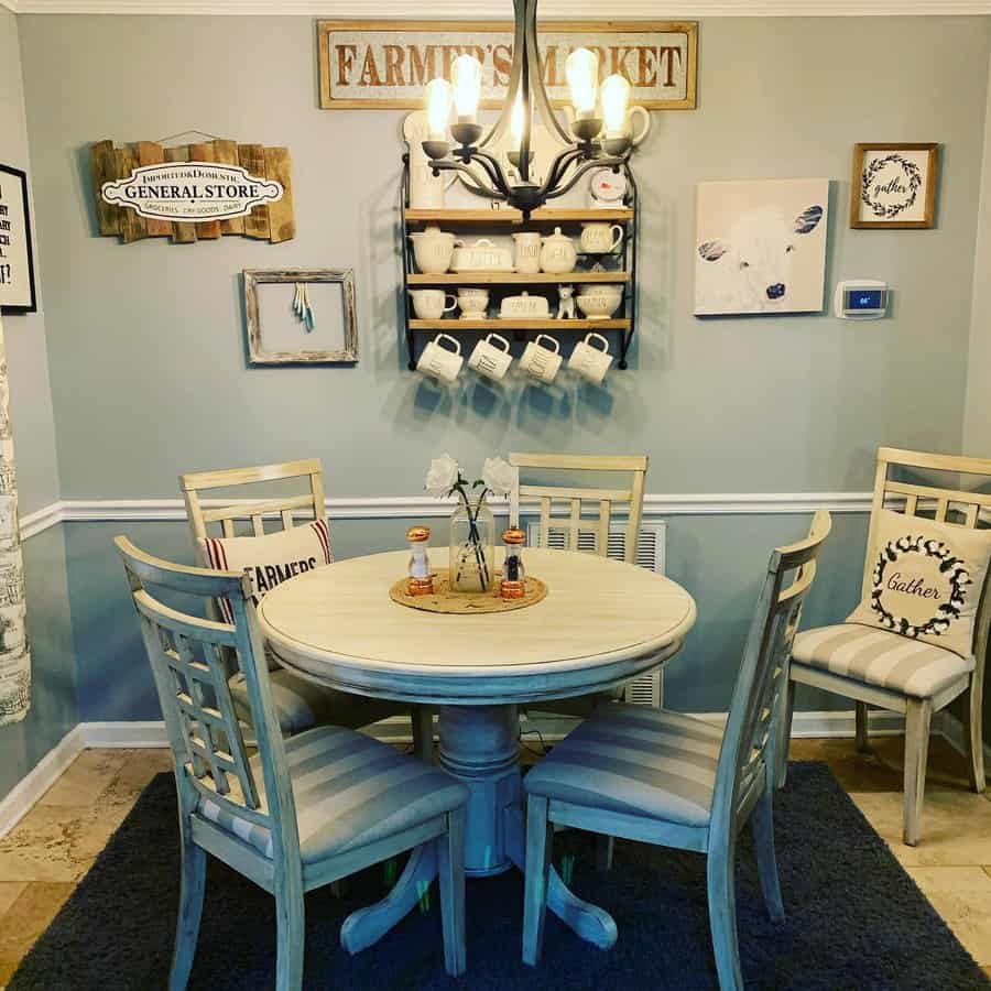 Rustic dining room with a round table, four chairs, rustic decor, wall signs, and a black chandelier displaying mugs