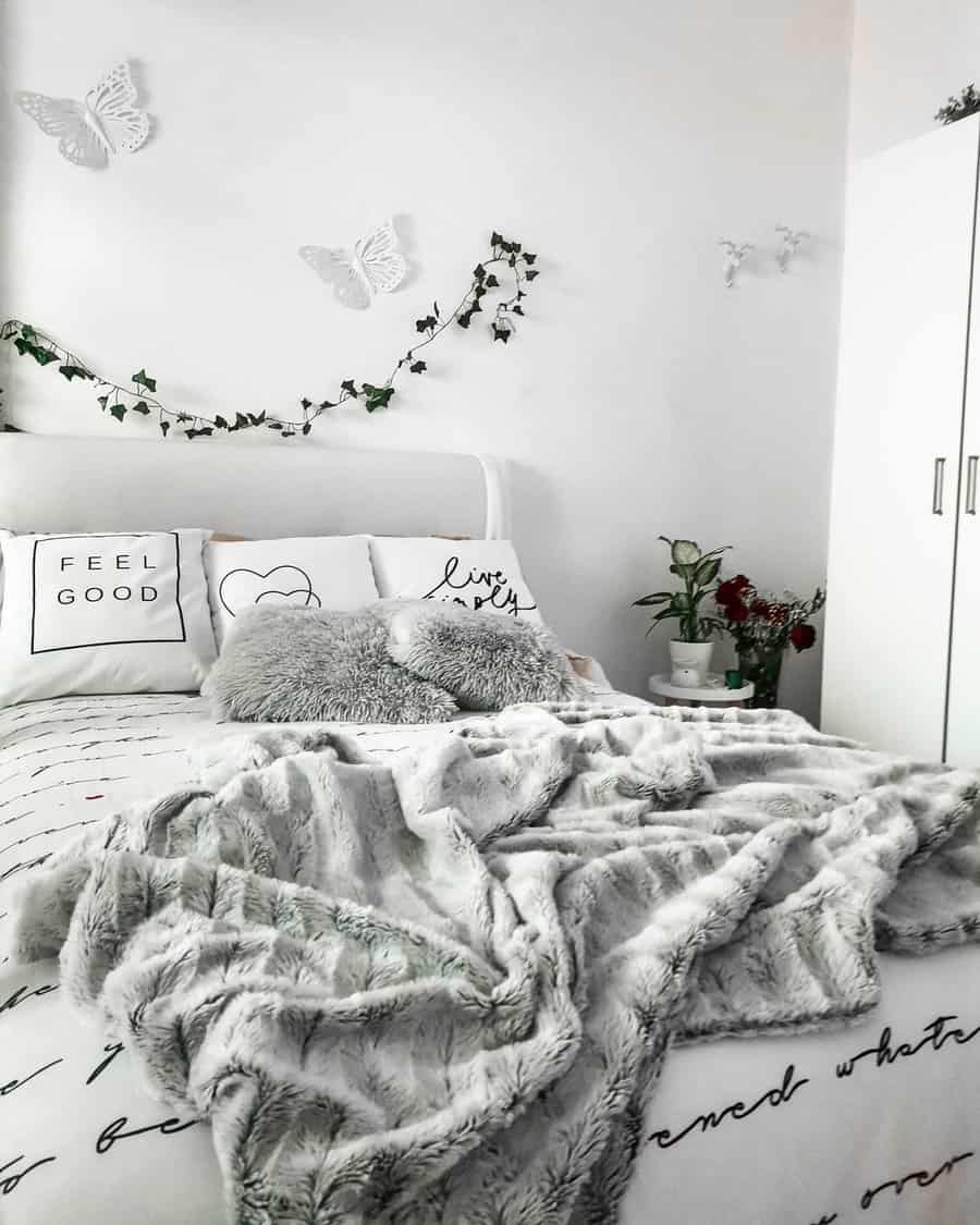 Scandinavian bedroom with white and gray bedding, decorative pillows, and wall ivy; butterfly accents and flowers add elegant touches