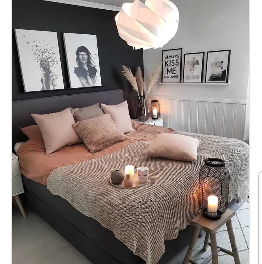 Cozy scandinavian bedroom with a dark accent wall, soft pillows, a beige knit throw, and candlelit decor; art and photos adorn the walls