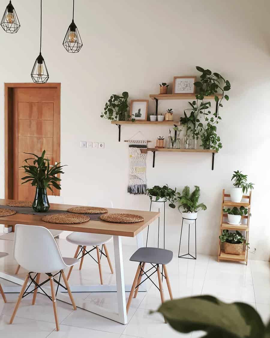 Minimalist dining room with wooden table, white chairs, hanging lights, and wall-mounted shelves with plants and decor