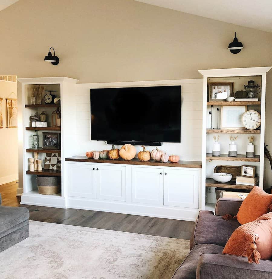 Cozy living room with shelves, TV, pumpkins, and neutral-colored decor