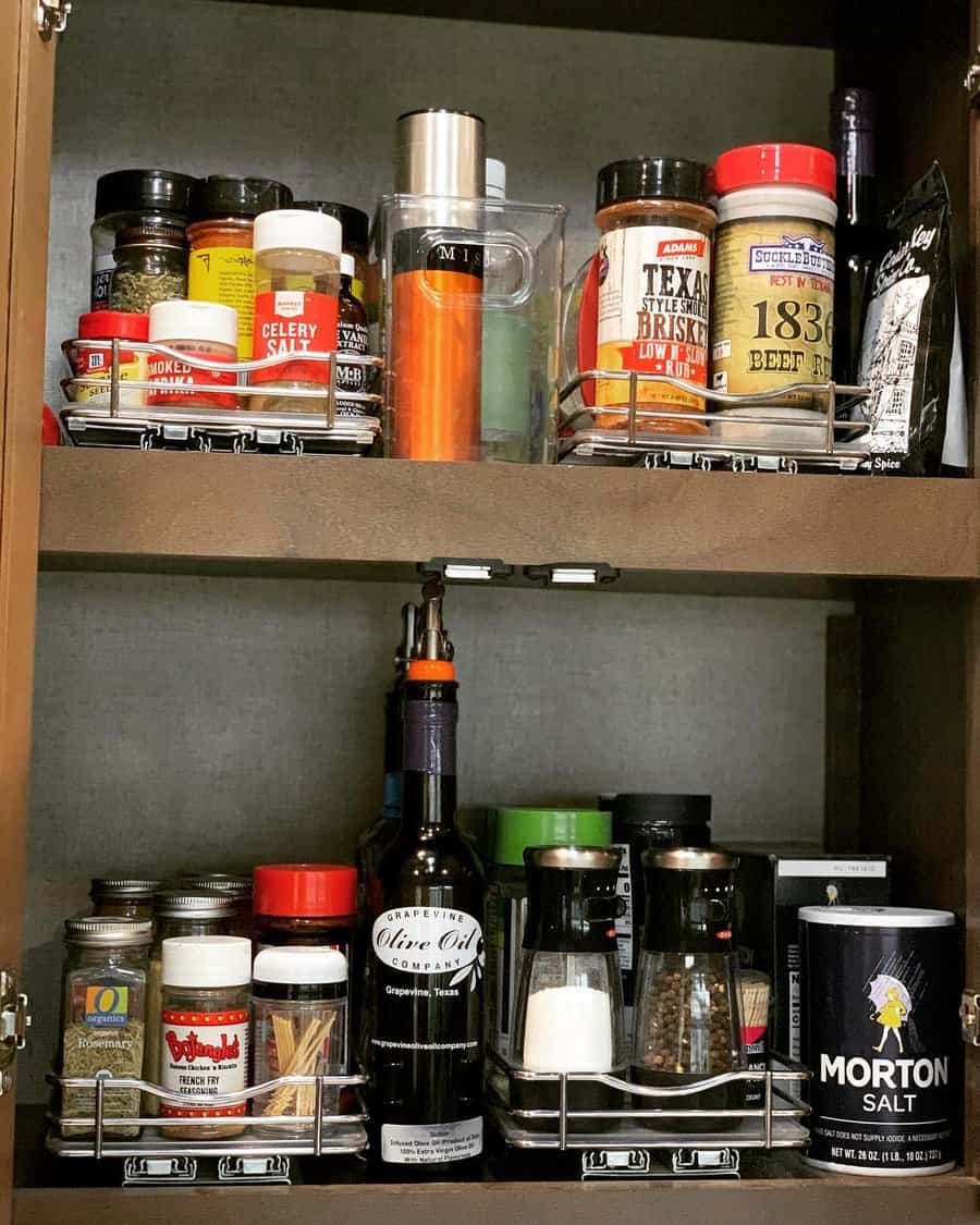 RV kitchen cabinet with organized spice racks, seasoning jars, and cooking essentials stored neatly on pull-out metal shelves.